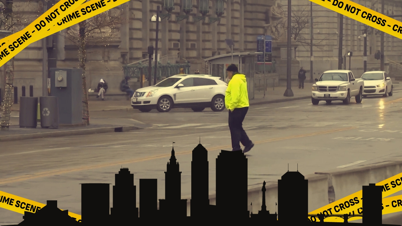 Man in a bright yellow jacket walks along a street in Cleveland, Ohio, with a "Do Not Cross - Crime Scene" tape overlaying the image and the city skyline silhouette at the bottom