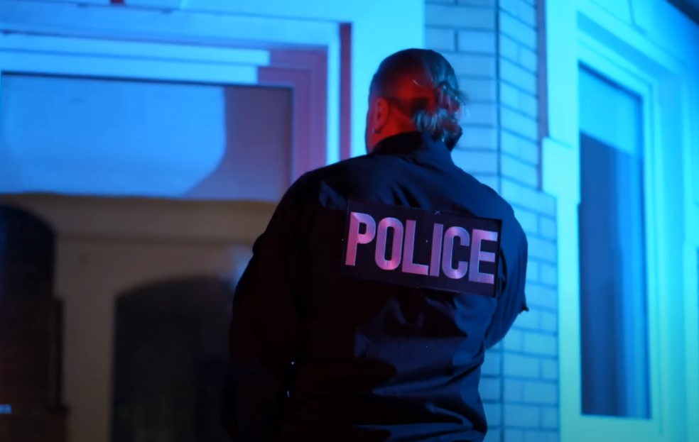 A woman police officer standing in front of the house doors