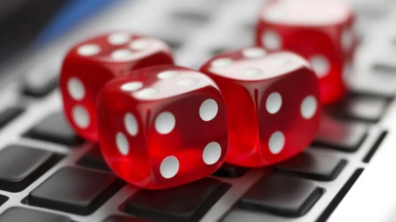 Close-up of four red dice placed on a computer keyboard, symbolizing online gambling and digital gaming