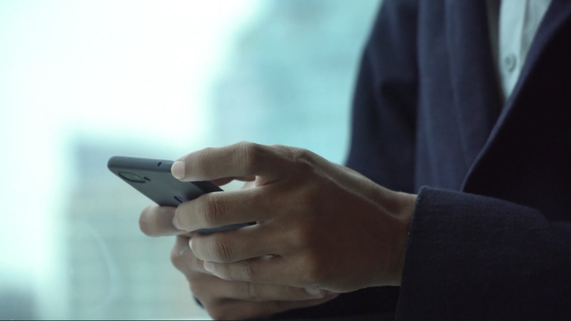 A person is holding a smartphone while avoiding accessing sensitive accounts in a public setting