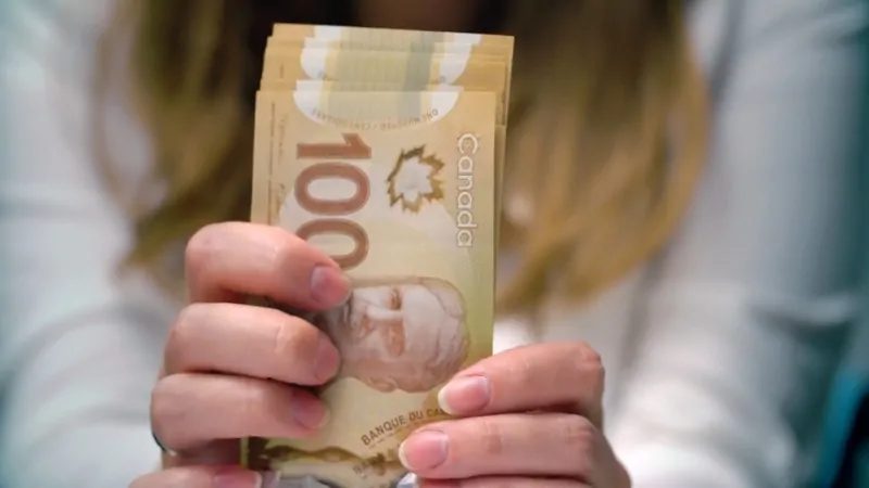 Person holding Canadian $100 bills while preparing for taxes in Canada