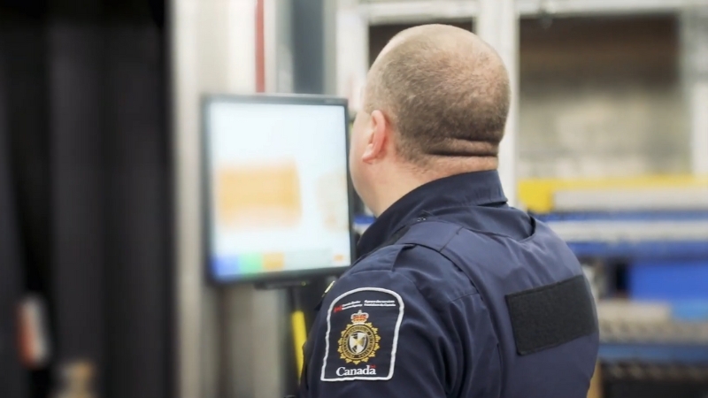 CBSA officer monitoring a screen, overseeing entry procedures and criminal history checks