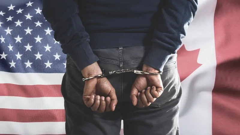 Person in handcuffs with U.S. and Canada flags, showing the impact of a criminal record on immigration