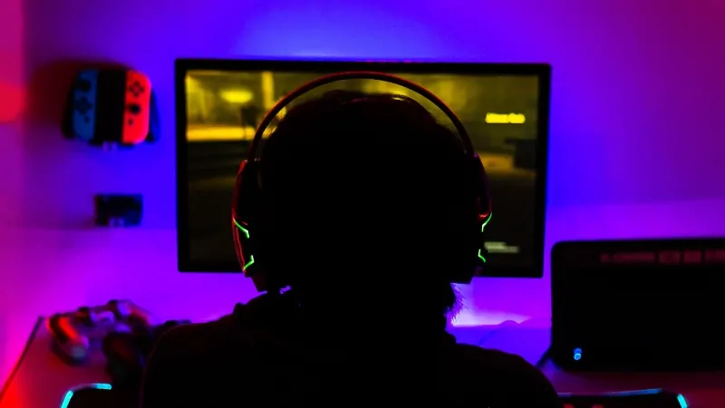 A gamer plays at a neon-lit PC setup inspired by top gaming developers
