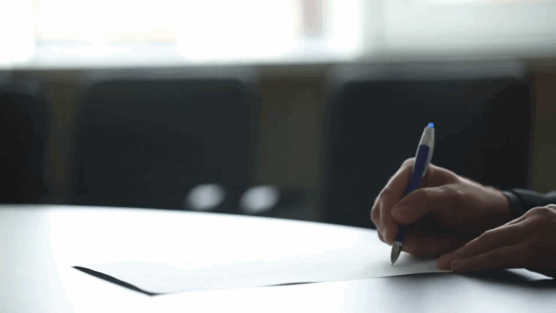A person writes on a document at a table, symbolizing civil penalties for accessing pirated content
