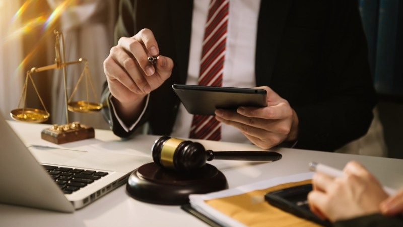 A lawyer reviews documents at a desk with a gavel and scales, showing criminal penalties for pirate streaming in Canada
