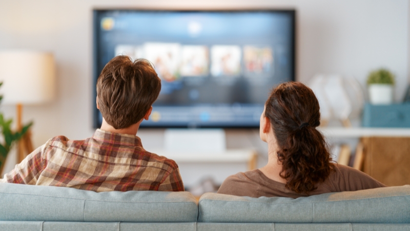 Two people sitting on a couch watching anime on TV at home