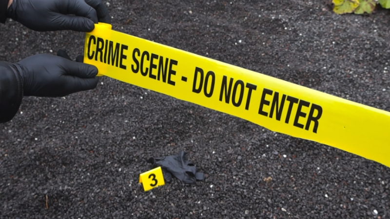 Police tape blocks off a crime scene with evidence markers on the ground