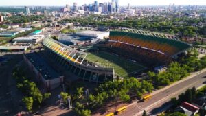 A packed Canadian stadium seen from above with clear views of the field, stands, and surrounding city