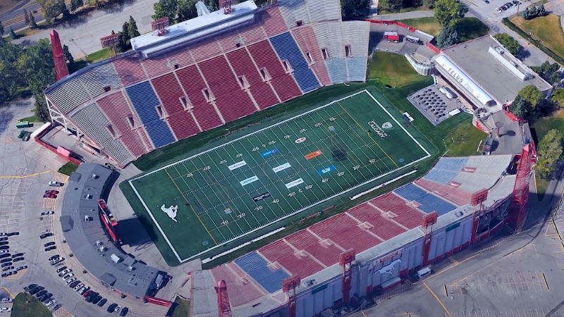 A quiet Canadian football stadium captured from above with empty red and blue seating around the field