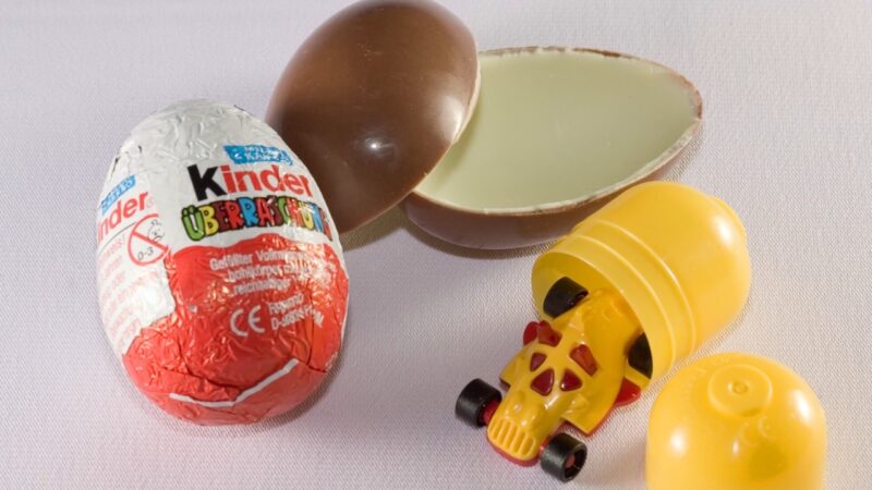 Kinder Surprise egg with a chocolate shell, toy capsule, and small toy car.